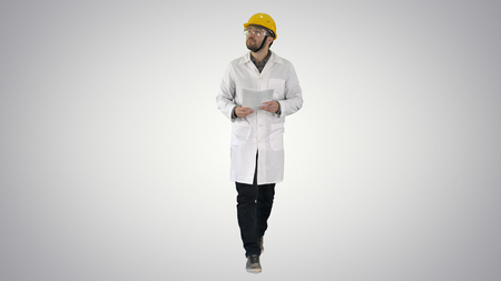 Engineer checking papers and looking around to sides on gradient background.の写真素材