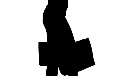 Silhouette Young woman with shopping bags walking out from shop.の写真素材