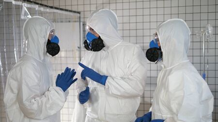 Group of doctors in protective suits having serious discussion.
