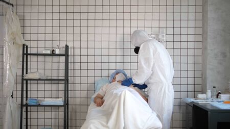 Doctor in Hazmat Sterile Suit Holding Hand of Male Patient Trying to Inspirit him.
