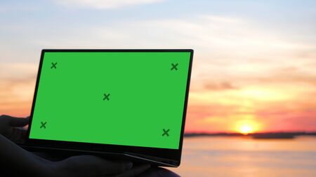 Young Woman Watching Content on laptop at sunset.の写真素材