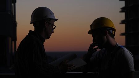 Medium shot.Construction workers having discussion at sunset. One smokes. Professional shot 025.の写真素材
