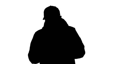 Silhouette Young casual man walking making a call wearing warm clothes and protective mask.の写真素材