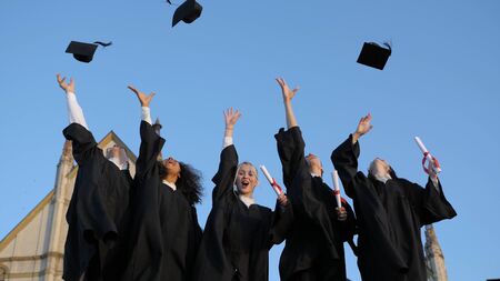 Group of graduates throwing their caps up in the air happily.の写真素材