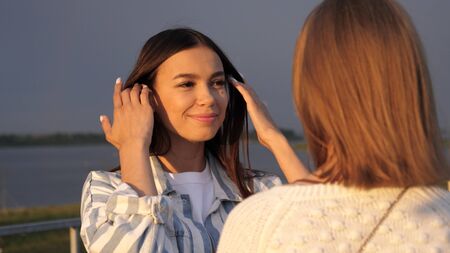 Two young ladies talk while waiting for their friend.
