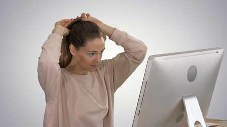 Office Lady in pink pullover with a Pony tail hair working on computer on gradient background.の写真素材