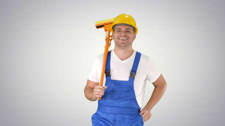 Housecleaner in helmet walking with a mop on gradient background.