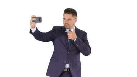 Handsome man in suit taking a selfie while walking on white background.の写真素材