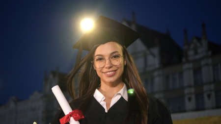 Happy beautiful young female graduate smiling to camera.
