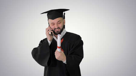 Happy graduated young man in cap and gown talking with a friend