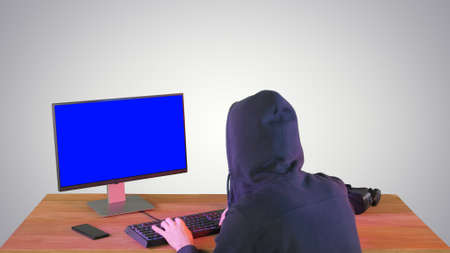 Hacker in hood cracking code using pc on gradient background.