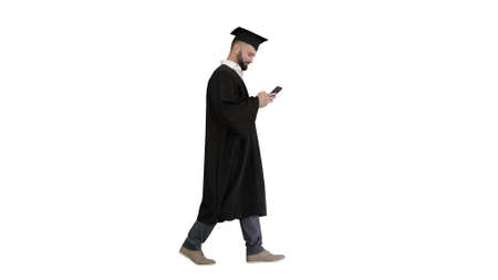 Graduate student walking and texting message on the phone on whiの写真素材