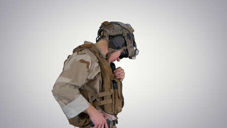 Soldier standing and talking on the radio on gradient background