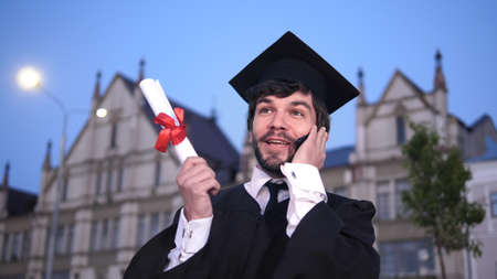 Graduation: Happy Student Calling Friends After Graduation.の写真素材