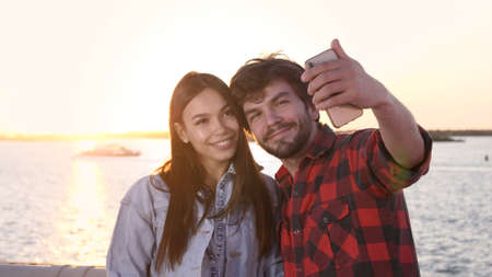 The attractive casual man and a woman taking a selfie with a sunset.