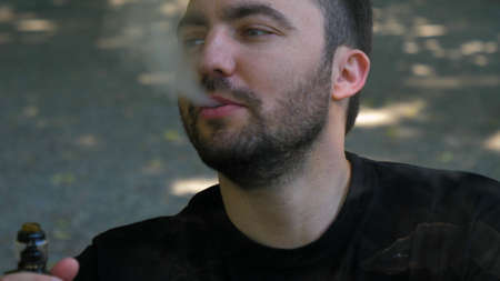 Handsome guy smoking an electronic cigarette outdoors.