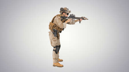Soldier aiming and shooting automatic rifle on gradient backgrouの写真素材