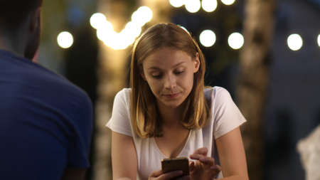 Attractive Young Woman on a date Using Mobile Phone and does not pay attention to the boy.の写真素材