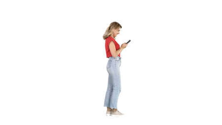 Casual young woman typing on mobile phone on white background.の写真素材