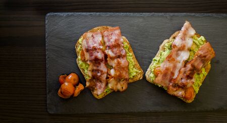 avocado toast with cherries tomatoes and baconの写真素材