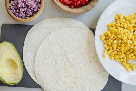 Ingredients for Mexican vegetarian tacos in bowls on light table, close-upの写真素材