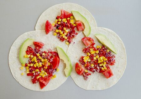 Mexican taco with vegetarian fillings on light table, cooking processの写真素材
