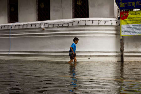 BANGKOK THAILAND - OCTOBER 29 : An unidentified boy is wallking through a flooded street on October 29, 2011 in Bangkok, Thailand.のeditorial素材