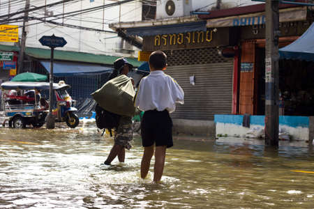 BANGKOK THAILAND - OCTOBER 29 : An unidentified boy and man walking  through a flooded street on October 29, 2011 in Bangkok, Thailand.のeditorial素材