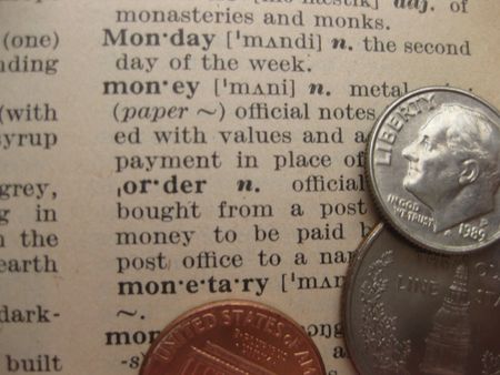 coins on a dictionary explaining the word moneyの写真素材