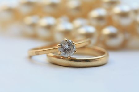 Diamond engagement ring and wedding band, pearls in the backの写真素材