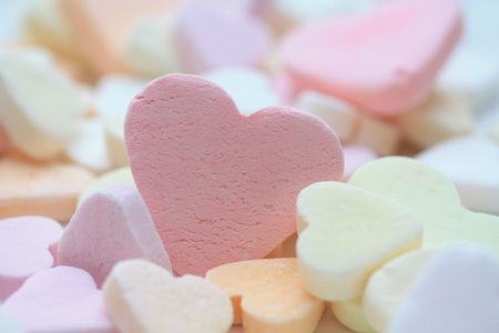 pink fruit candy heart on a pile of candy heartsの写真素材