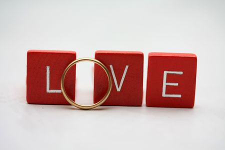 Red wooden letters with a simple yellow gold wedding band.の写真素材