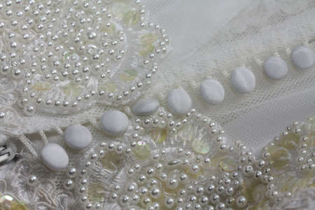Detail of a white bridal gown or wedding dress with pearls and white buttonsの写真素材