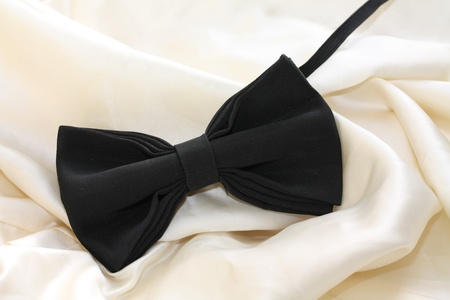 A black silk bow-tie on white satin, grooms accessory on his wedding dayの写真素材