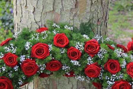 Red roses and white gypsophila in a funeral wreath, detail near a treeの写真素材