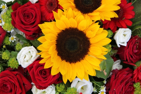 Bright yellow sunflowers and big red roses in a floral arrangementの写真素材