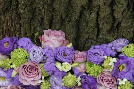 Mixed purple floral arrangement near a tree