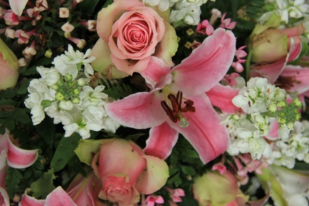 Pink lillies and roses in a pink and white wedding flower arrangementの写真素材