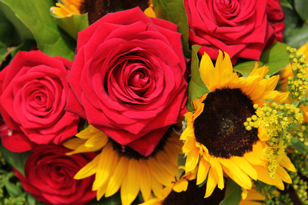 Big red roses and sunflowers in a floral arrangementの写真素材