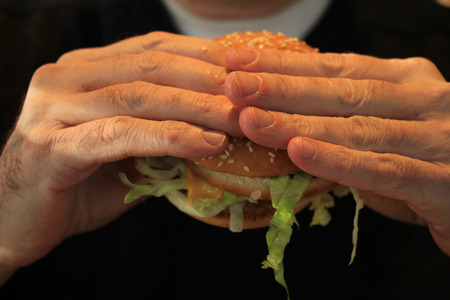 Man holding his hamburger, close up of hamburgerの写真素材