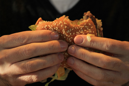 Man holding his hamburger, close up of hamburgerの写真素材