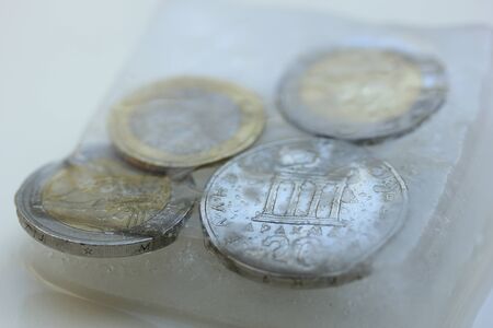 Frozen Assets: Greek euro and Drachme coins in iceの写真素材