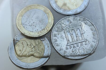 Frozen Assets: Greek euro and Drachme coins in iceの写真素材