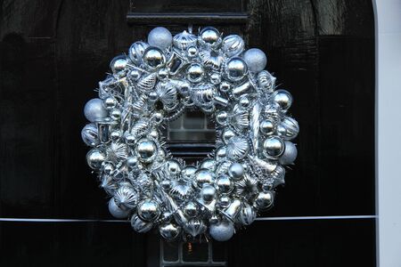 Silver christmas wreath with decorations on a doorの写真素材