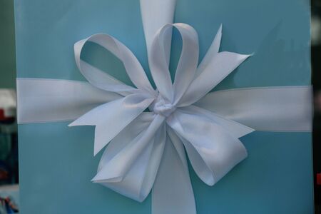 White satin bow on blue giftboxの写真素材