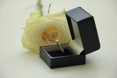 Classic solitaire engagement ring in box and white rose
