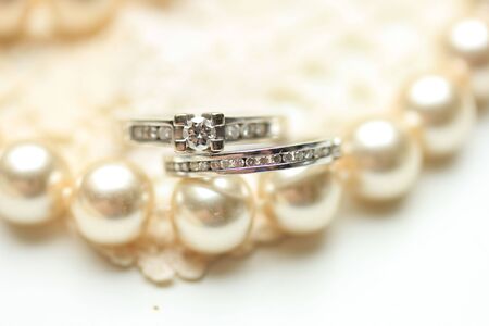 Engagement ring and wedding band with diamonds on a pearl necklaceの写真素材