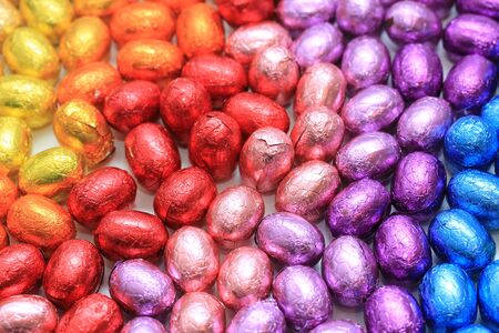 a group of foil wrapped chocolate easter eggs in rainbow colors