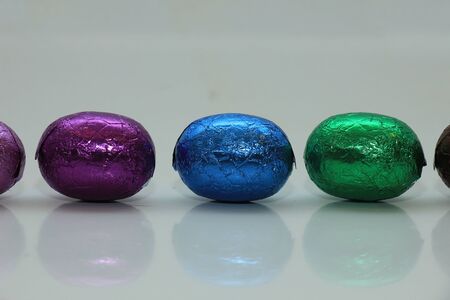 colorful wrapped chocolate easter eggs in a rowの写真素材