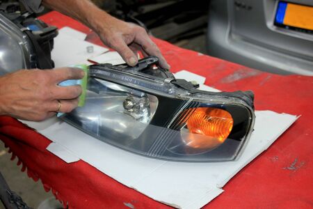 Man refurbishing a car headlight with clear coatingの写真素材